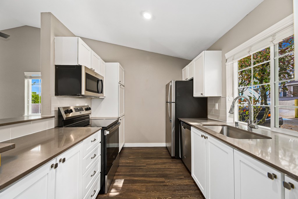 A kitchen with black appliances and white cabinets.