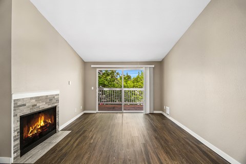 A room with a fireplace and a view of a balcony with trees.