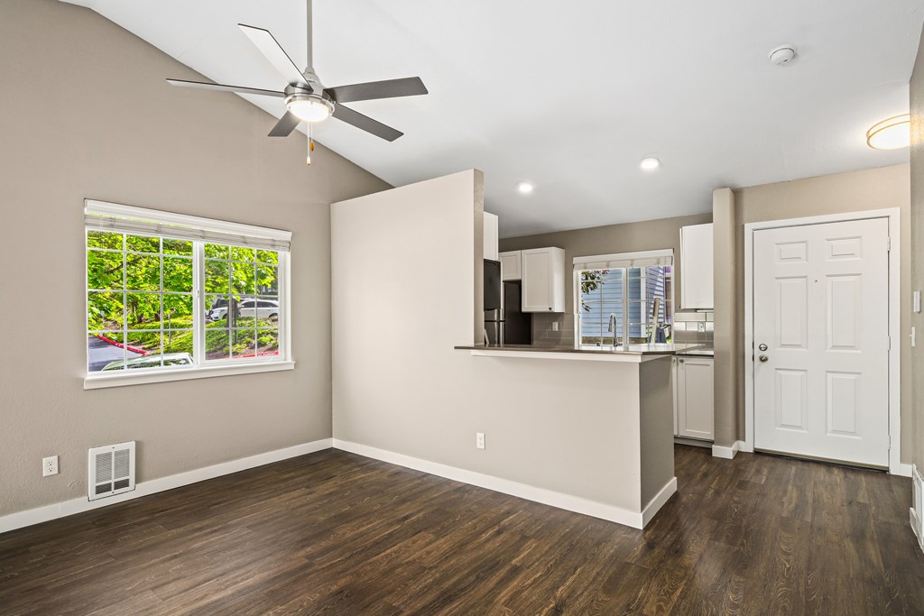 A room with a ceiling fan and a window with a view of a garden.