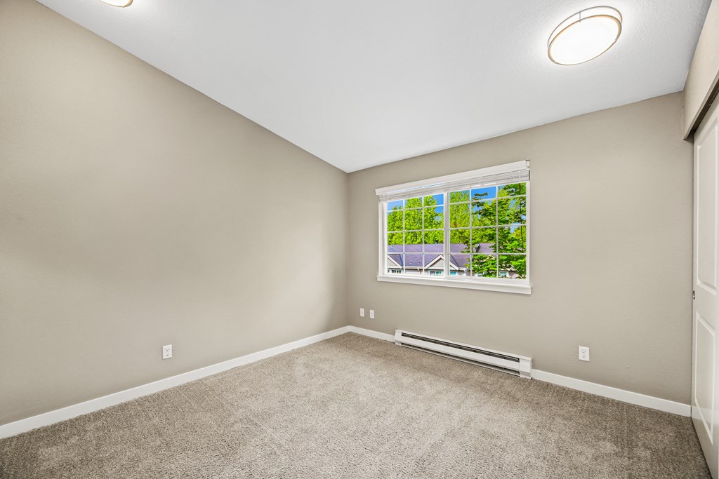 A room with a window showing a view of a house and trees.