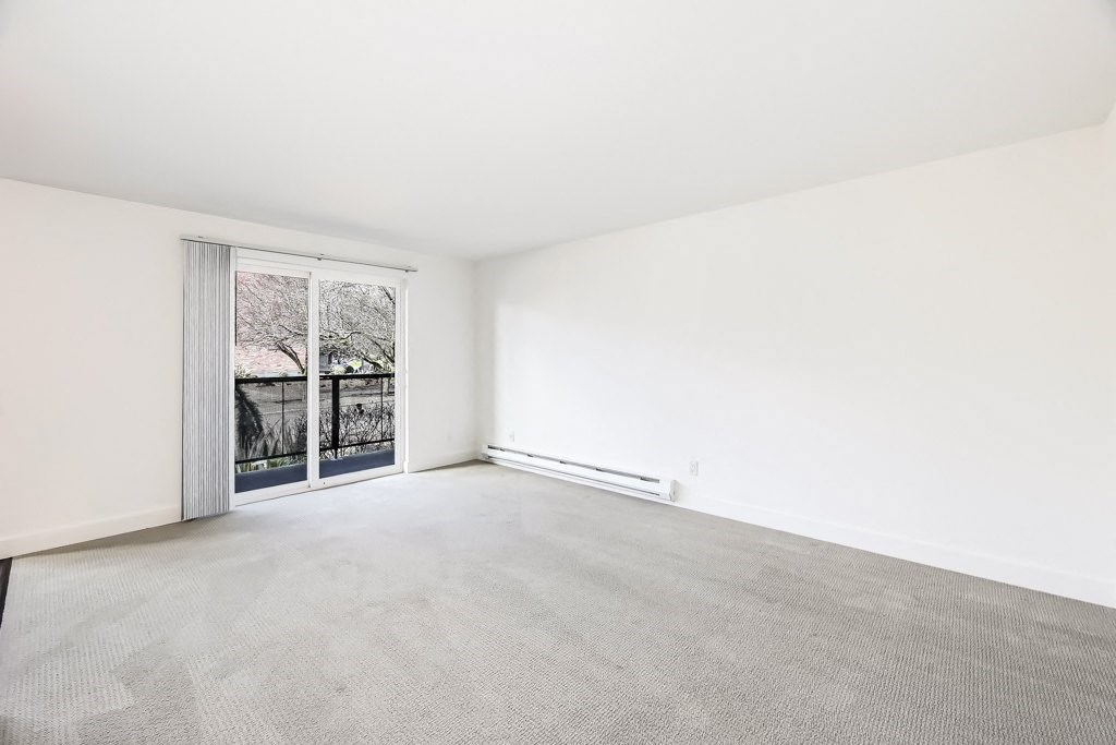 an empty living room with a large window and white walls