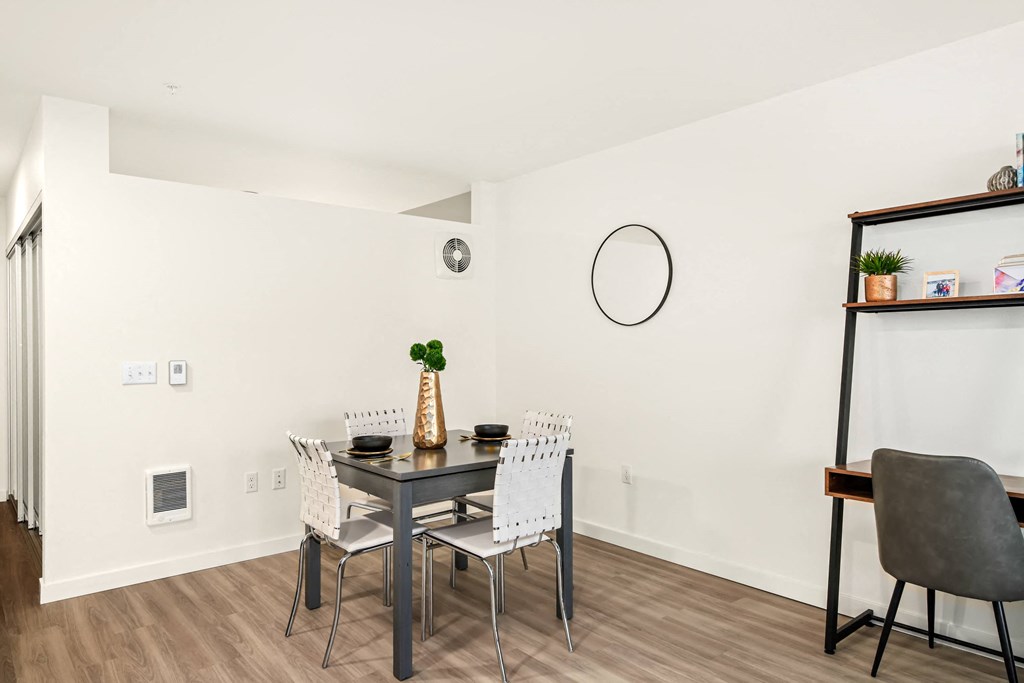 A dining table with four chairs and a vase with a green plant on it.