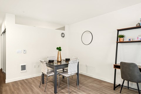 A dining table with four chairs and a vase with a green plant on it.