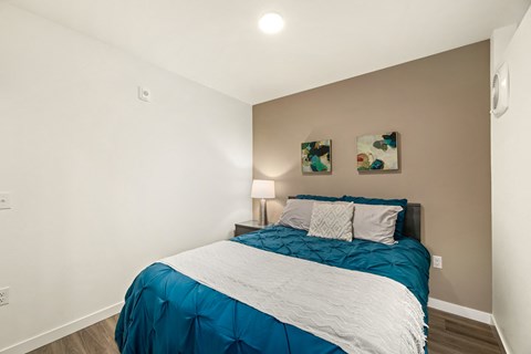 A bed with a blue and white comforter is in a room with two wall art pieces.