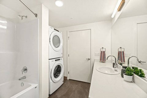 A white bathroom with a washing machine in the corner.