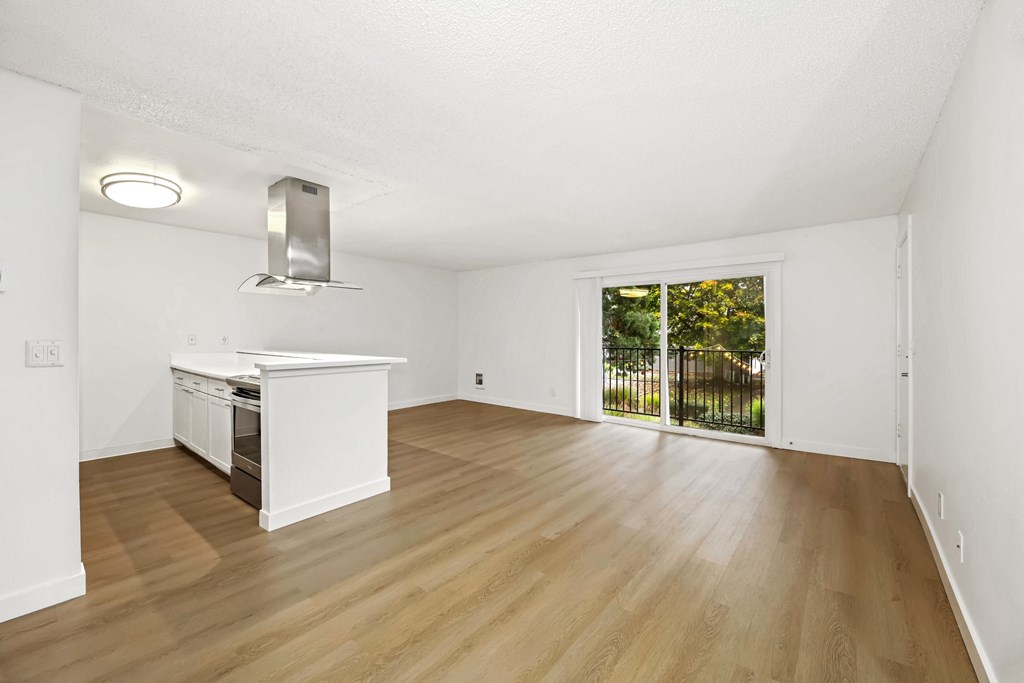 A white kitchen with wooden floors and a window.