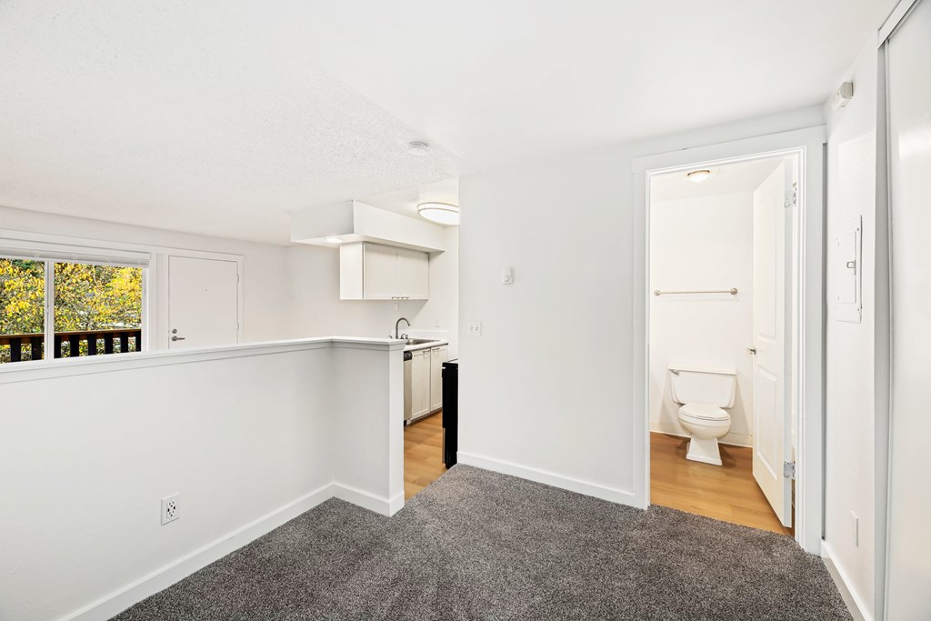 A white bathroom with a toilet and a window.