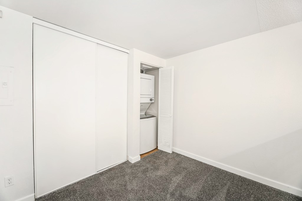 A white closet with a door and a shelf.