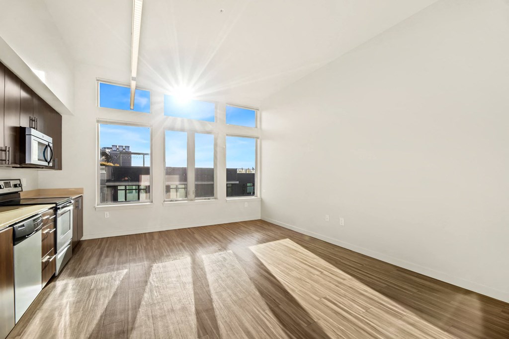 A sunny day in a kitchen with wooden floors and a window overlooking the city.