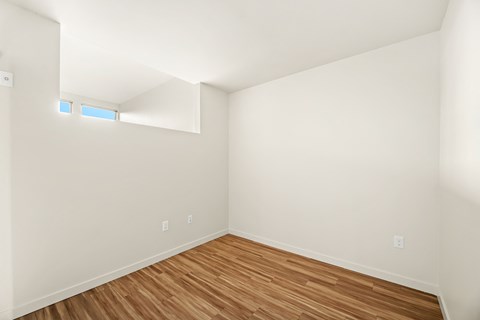 A room with wooden flooring and white walls.
