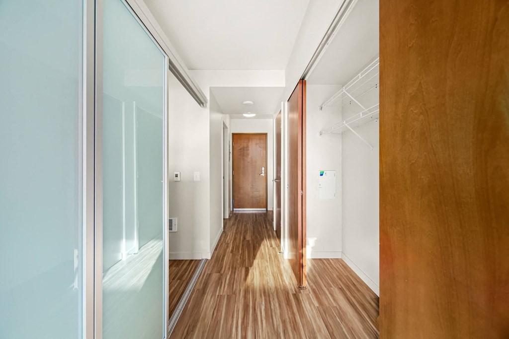 A long hallway with a wooden floor and a door at the end.