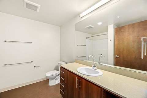 A bathroom with a toilet, sink, and mirror.