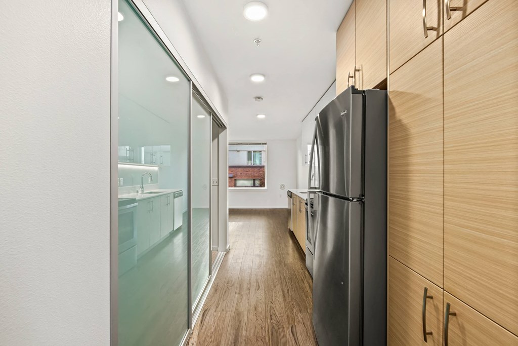 A modern kitchen with a black refrigerator and wooden cabinets.