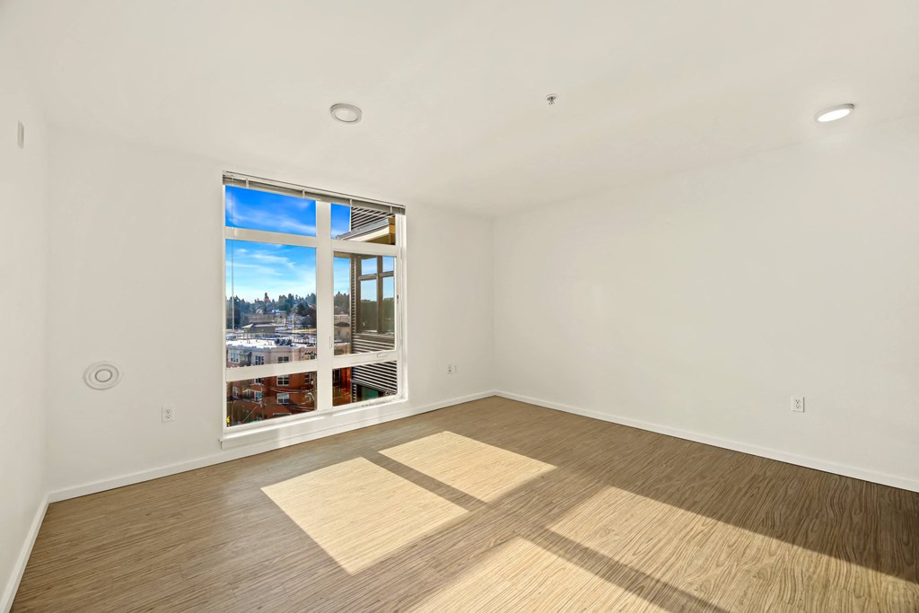 A room with a large window and wooden flooring.