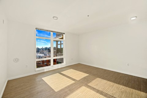 A room with a large window and wooden flooring.