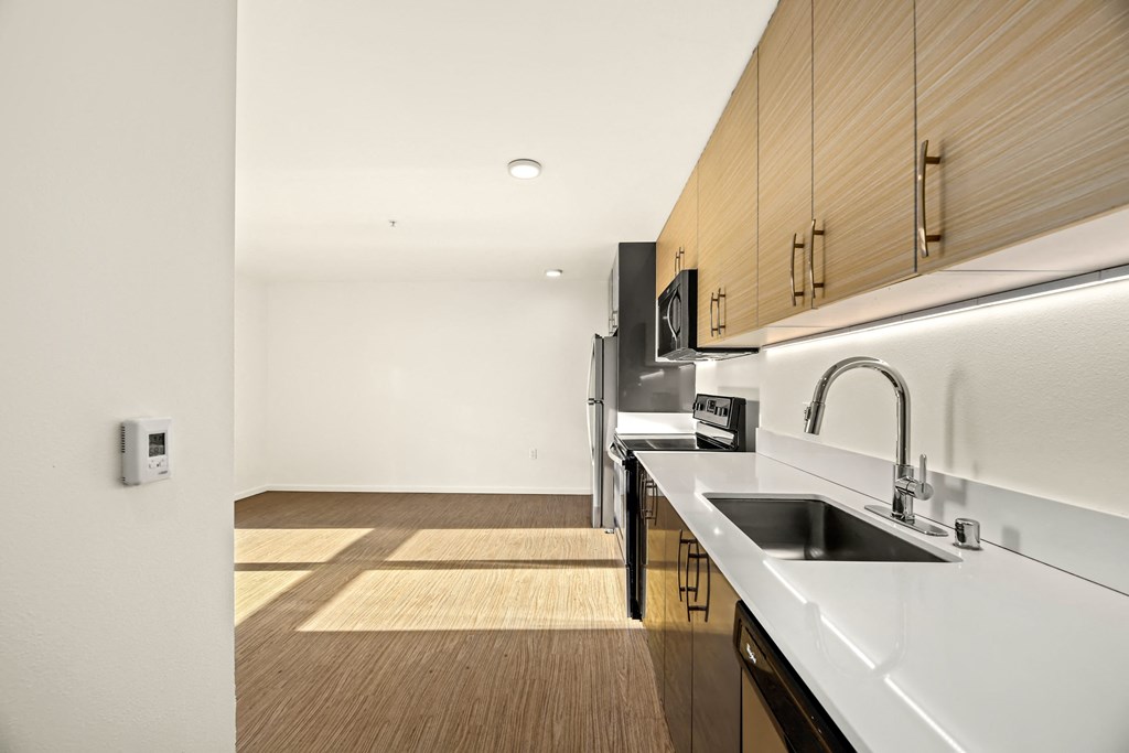 A modern kitchen with a white counter top and wooden cabinets.
