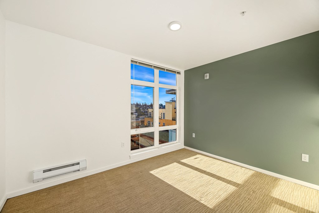 A room with a window showing a view of a cityscape and a balcony.