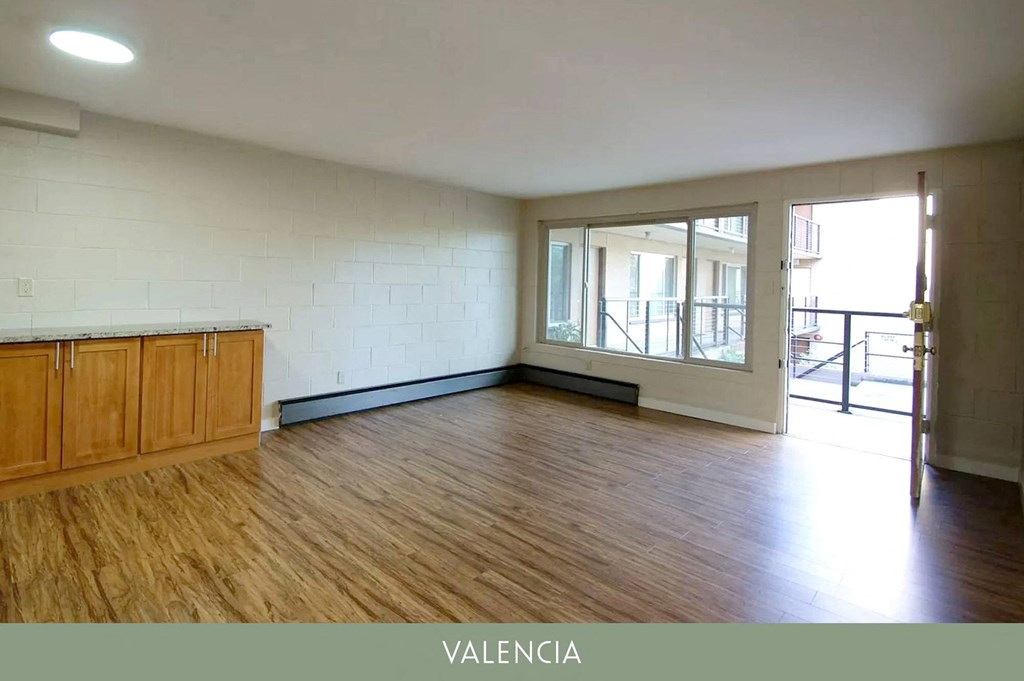 an empty living room with wood flooring and a balcony