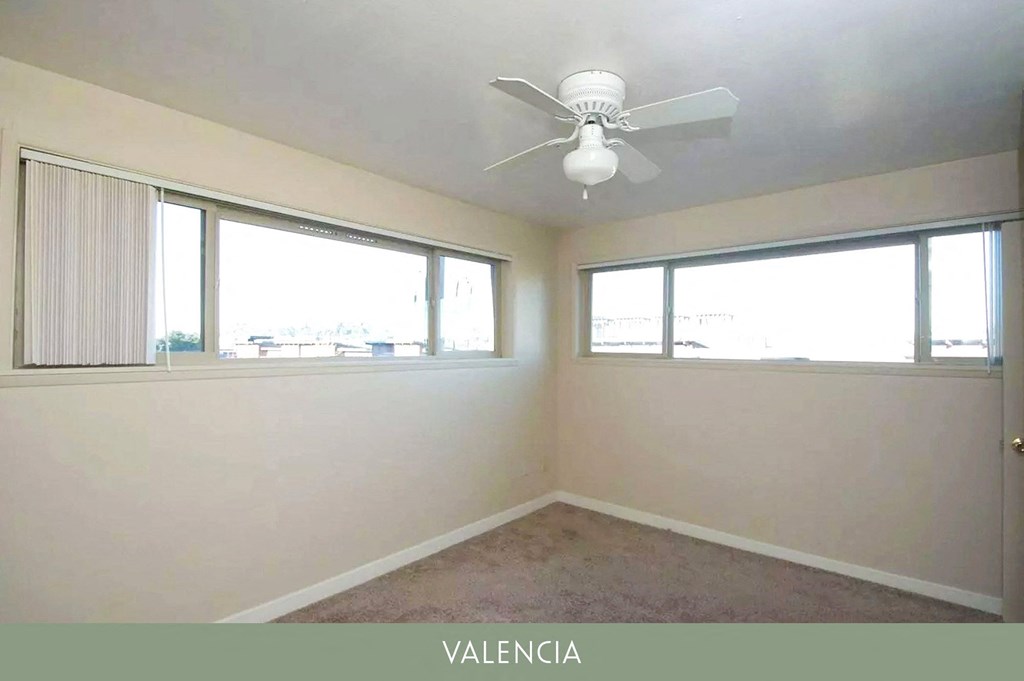 a bedroom with a ceiling fan and three windows