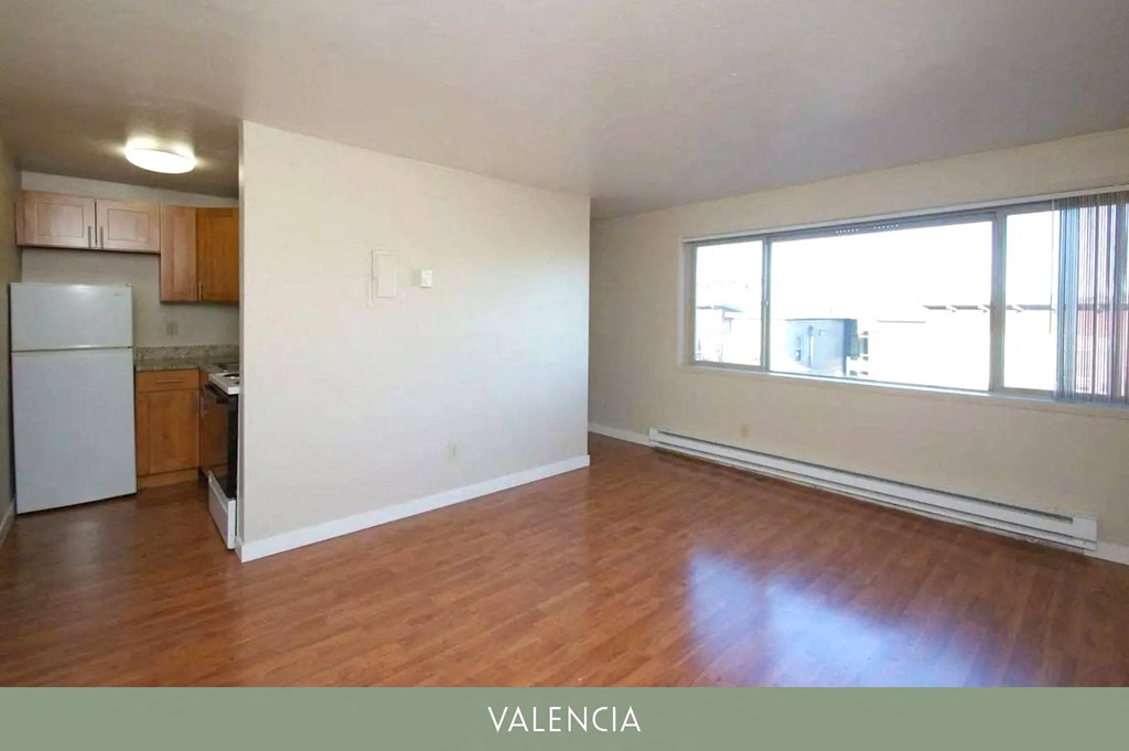 an empty living room with wood flooring and a large window