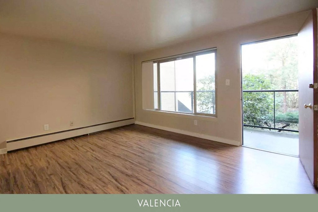 an empty living room with a large window and wooden floors