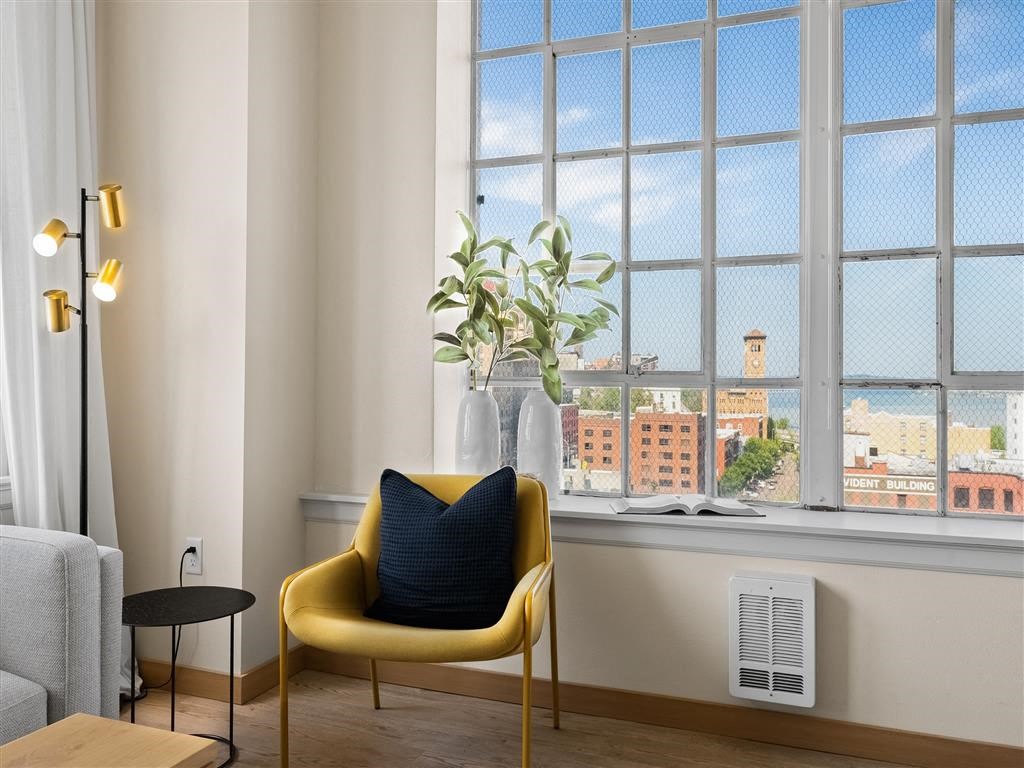 a chair in front of a window with a blue pillow and a plant in a vase