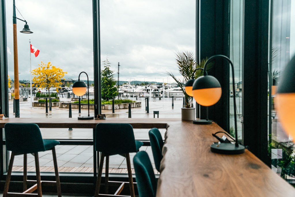 a restaurant with a wooden table and chairs overlooking a marina