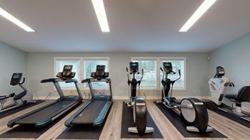 A gym with treadmills, elliptical machines, and exercise bikes.