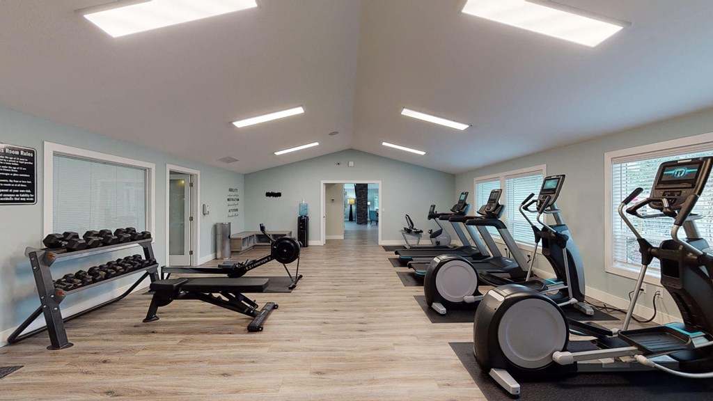 a gym with cardio machines and weights on a wooden floor