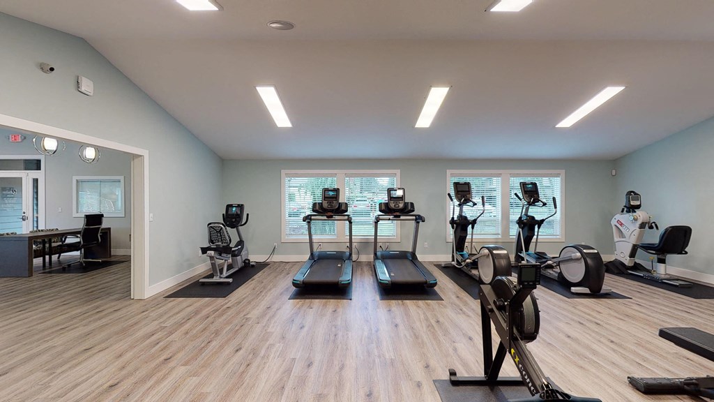 a gym with cardio machines and weights on a wooden floor