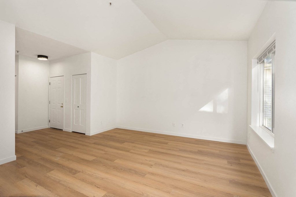 an empty living room with white walls and wood floors