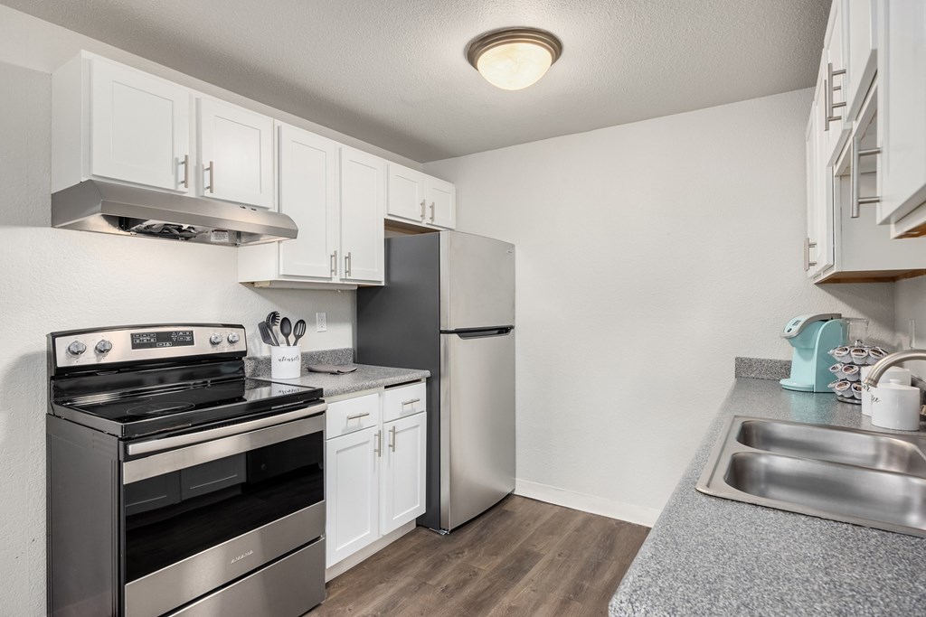 A kitchen with a stove, refrigerator, and sink.