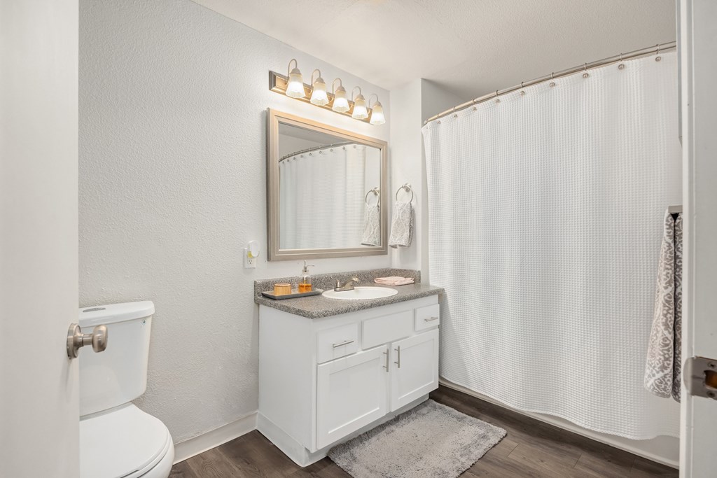 A white bathroom with a toilet, sink, and shower.