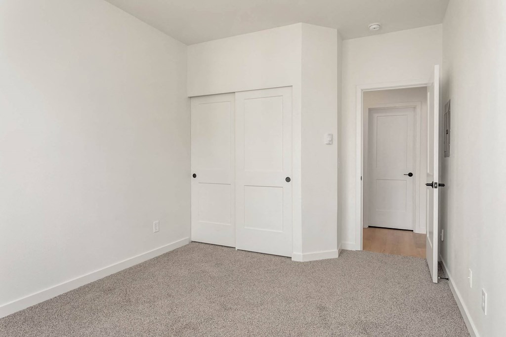 a bedroom with white walls and white doors and a carpeted floor