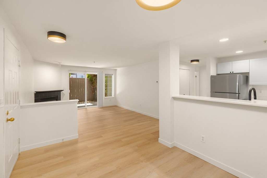 a renovated living room and kitchen with white walls and wood floors