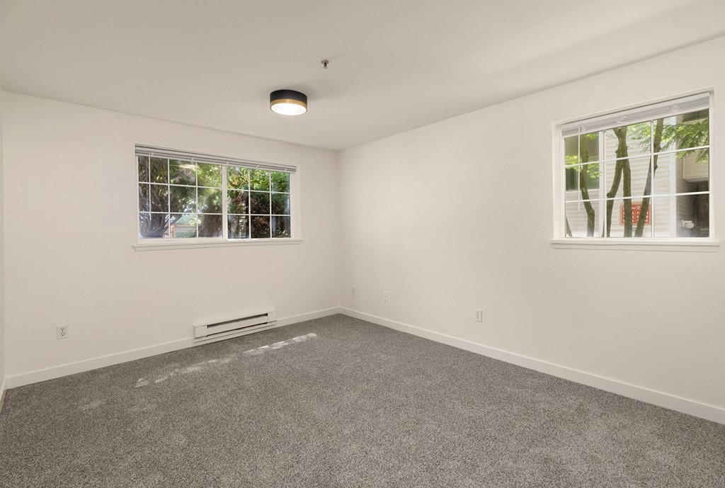 an empty room with carpet and two windows