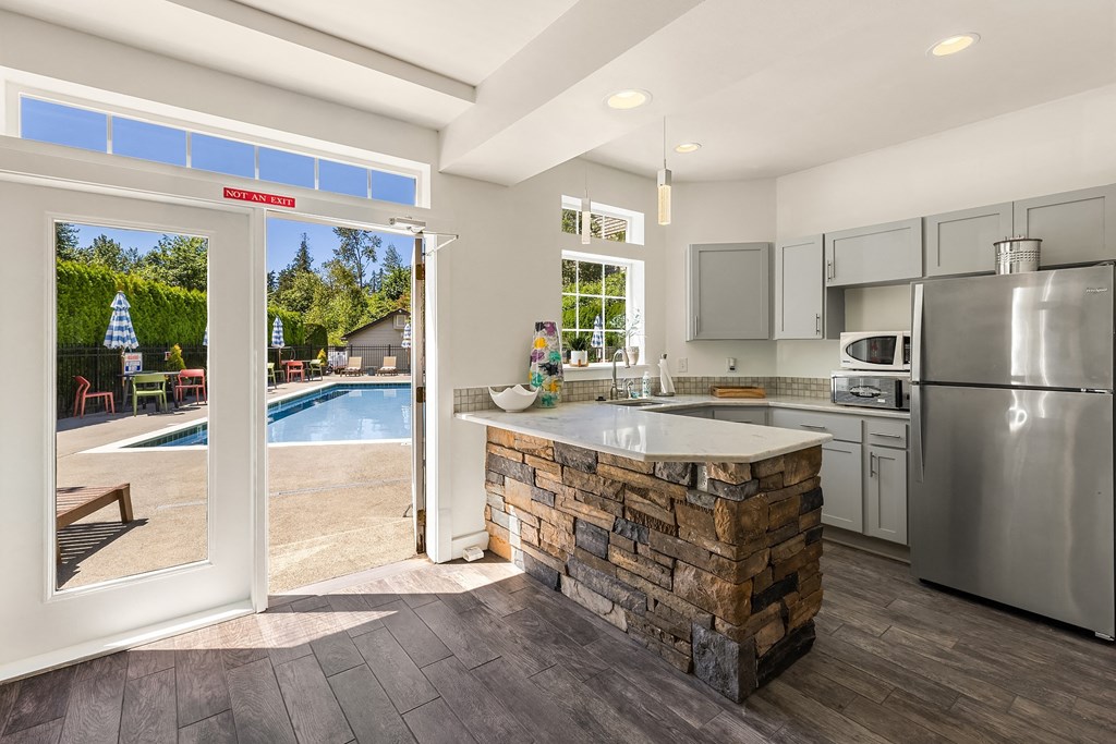 kitchen with stainless steel appliances and a stone island with a view of a swimming pool
