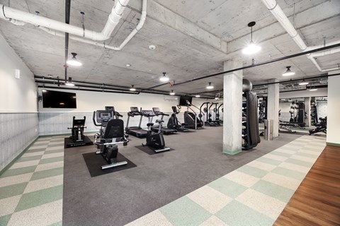 A gym with a variety of equipment including treadmills, weights, and exercise machines.