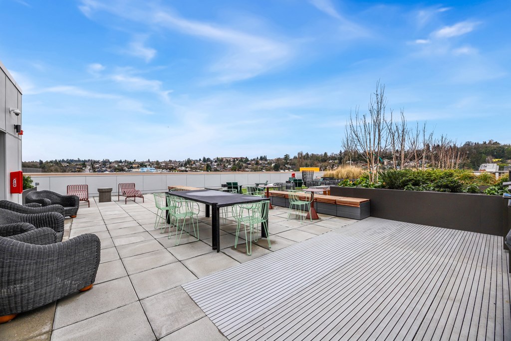 A rooftop patio with a table and chairs overlooking a city.