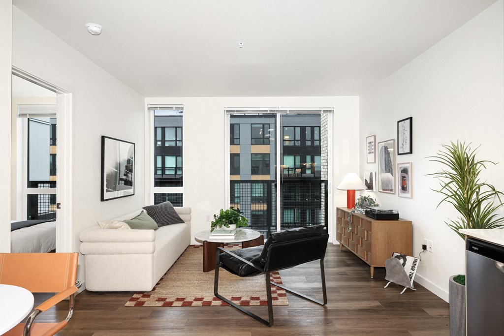 A living room with a white couch, a black chair, and a red and white rug.