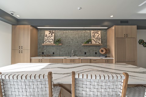 A modern kitchen with a marble table and wooden chairs.