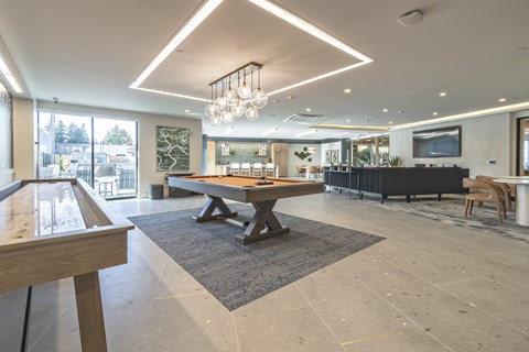 A modern dining room with a pool table and a large TV.