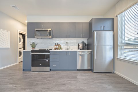 A modern kitchen with stainless steel appliances and grey cabinets.
