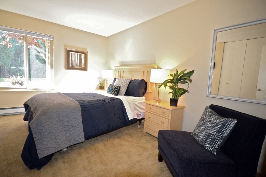 a bedroom with a bed and a chair and a window