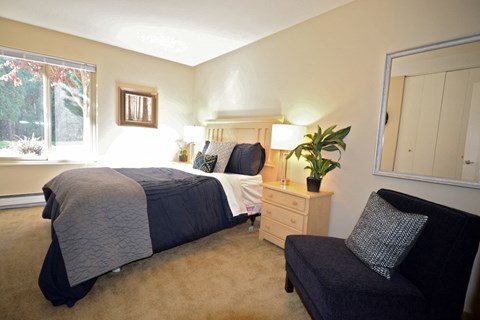 a bedroom with a bed and a chair and a window