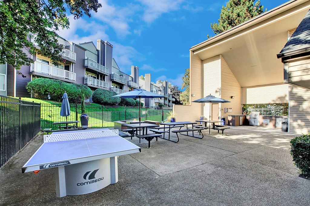 a patio with tables and umbrellas in front of an apartment building
