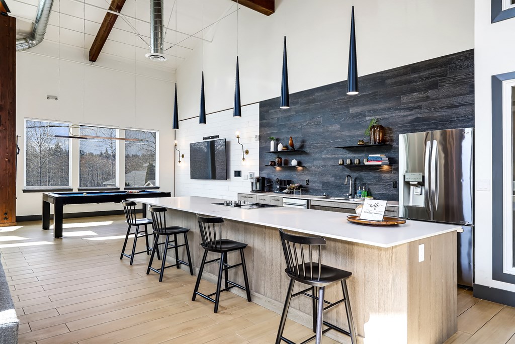 a kitchen with a large island and bar stools and a billiards table