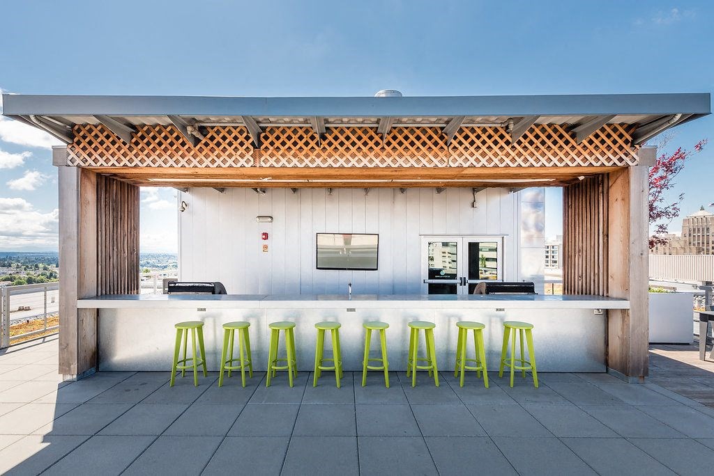 a rooftop bar with yellow stools and a white wall