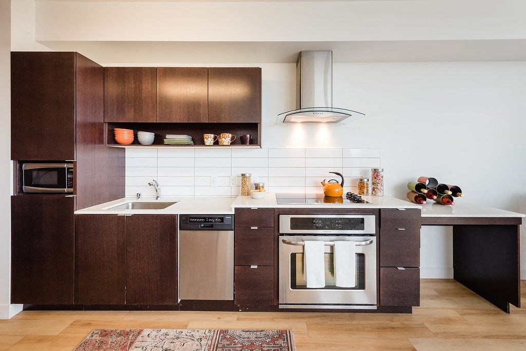 a kitchen with dark wood cabinets and white countertops