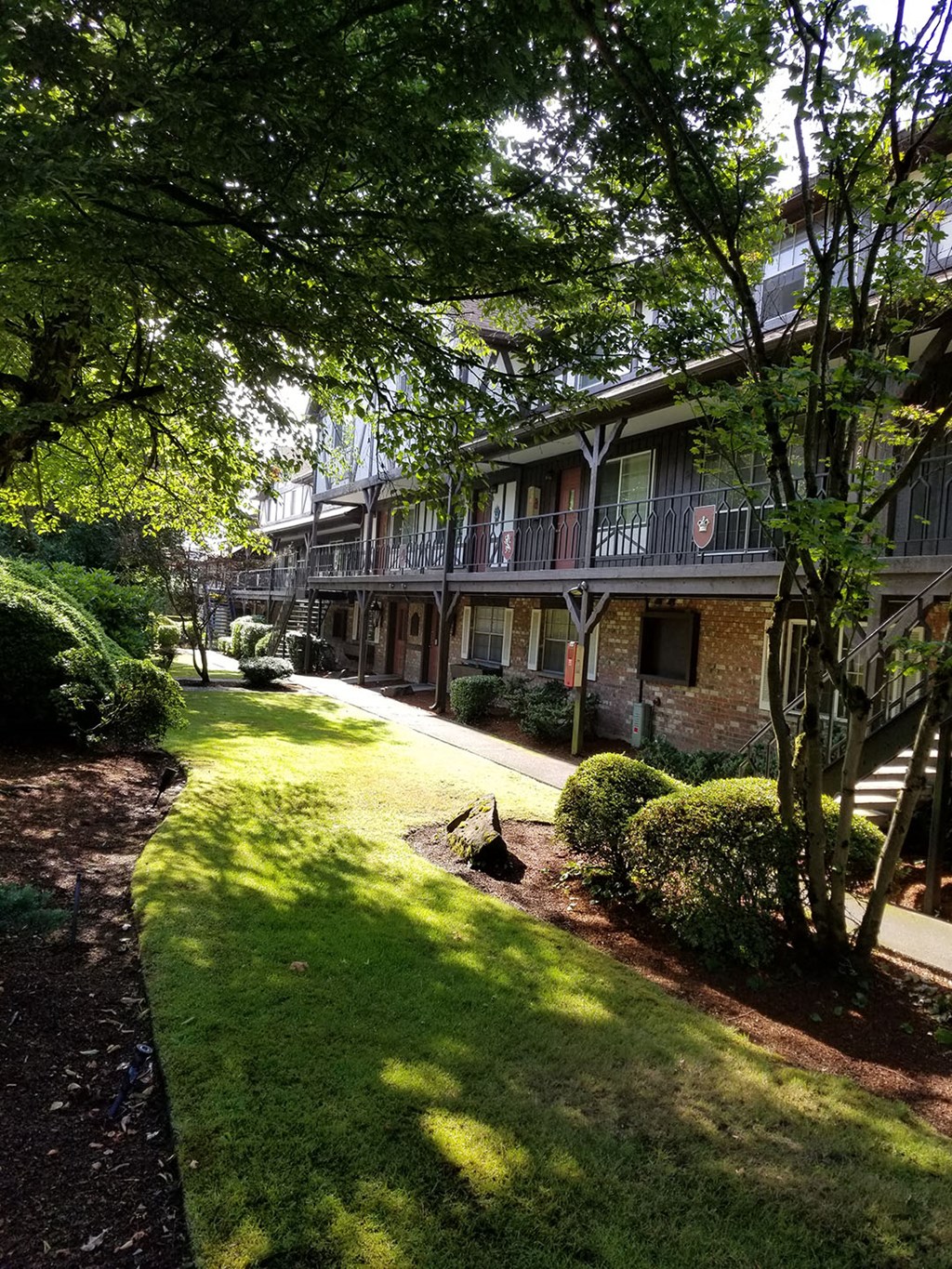 a sidewalk in front of a building with green grass and trees